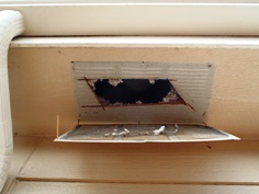 Image of another soffit vent with a very small hole cut.