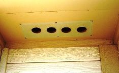 Image of 4 round holes drilled behind the soffit vent, not providing much airflow into the attic.